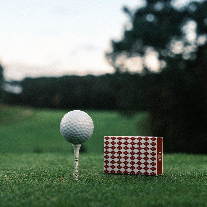 Red golf tee match box by Three Putt Round, featuring a collection of standard wooden golf tees inside a compact, portable container.