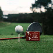 Set of red golf tees in a matchbox by Three Putt Round, compact golf tee holder with multiple tees inside.